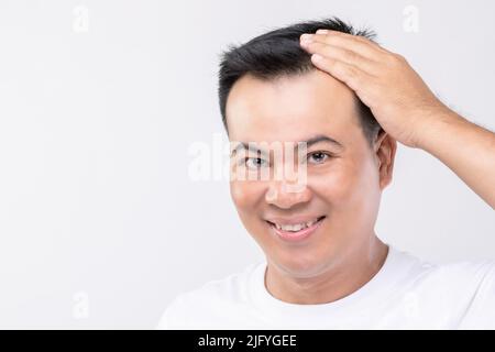 Portrait happy Asian man touching on his head to show bald head or Glabrous problem. Studio shoot with copy space with grey background Stock Photo