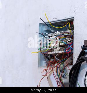 Open junction box with protruding wires, prepared for mounting and connecting telephone and computer cables. Selective focus Stock Photo