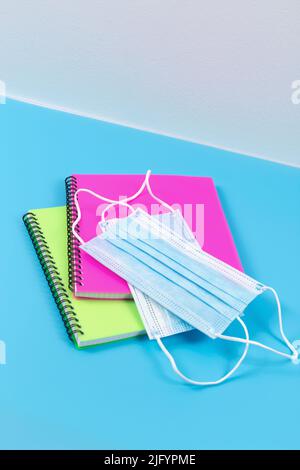 Two spiral notebooks and medical masks on blue table. Pandemic concept. Stock Photo