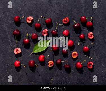 Cherry fruits pattern in a vibrant summer mood on black stone background Stock Photo