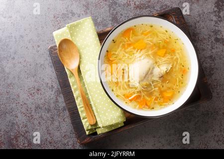 Polish Rosol z kury chicken soup with vermicelli and vegetables close-up in a bowl on a wooden tray on the table. horizontal top view from above Stock Photo