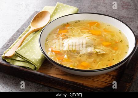 Polish Rosol z kury chicken soup with vermicelli and vegetables close-up in a bowl on a wooden tray on the table. horizontal Stock Photo