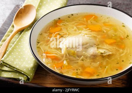 Dietary chicken soup with vermicelli and vegetables close-up in a bowl on a wooden tray on the table. horizontal Stock Photo