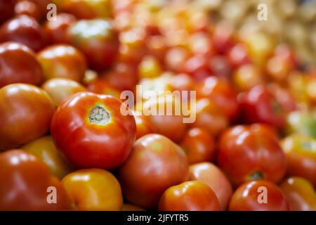 Selective focus on red tomato. Sale of fresh raw vegetable in market stall. Stock Photo