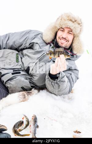 Portrait of smiling man holding a fish caught after ice fishing, Lapland, Sweden, Scandinavia, Europe Stock Photo