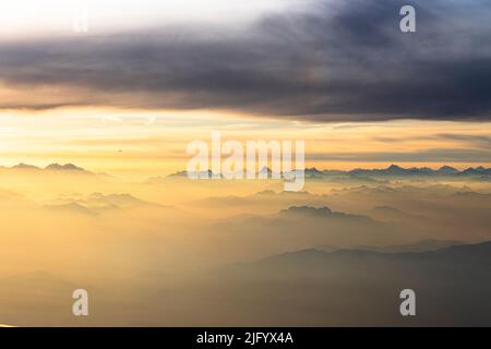 Flying over the majestic Swiss Alps in a sea of clouds at sunset, Switzerland, Europe Stock Photo