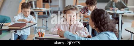 Happy kind teacher is helping kids in elementary school lessons Stock Photo