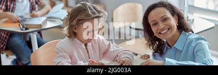 Happy kind teacher is helping kids in elementary school lessons Stock Photo