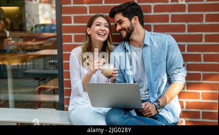 Beautiful young couple sitting in cafe, having fun with tablet. Students during break in the cafe. Stock Photo