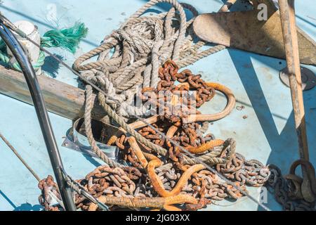 Sunny boat deck with mooring rope and rusty metal mooring chain. For UK sailing and boating activities. Stock Photo