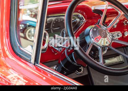 Andover, MA, US-June 26, 2022: Close-up view of the steering wheel in a bright red 1950s - 1960s era Chevrolet  classic car. Stock Photo