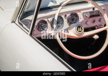 Andover, MA, US-June 26, 2022: Close-up of the steering wheel in white 1950s - 1960s era classic car at a local car show. Stock Photo