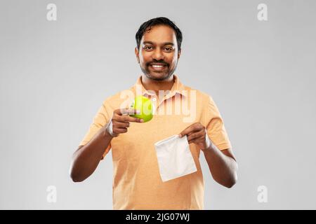 indian man with apple and reusable canvas bag Stock Photo