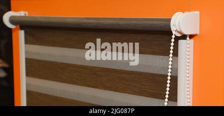 A close-up of a striped roller blind for a window, roller zebra blind, shutter installed on a window indoors. Stock Photo