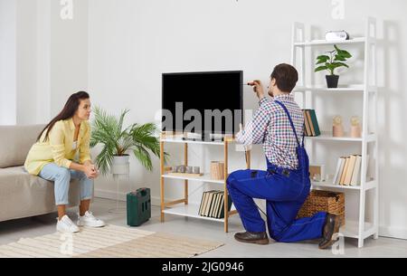 Female customer watch male mechanic repair TV Stock Photo