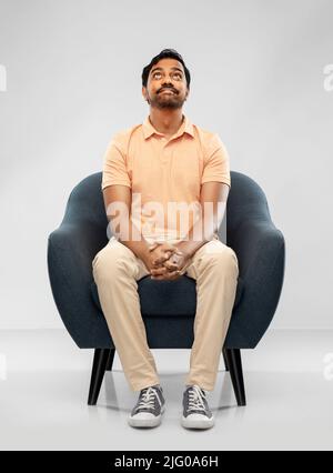 happy smiling young indian man sitting in chair Stock Photo