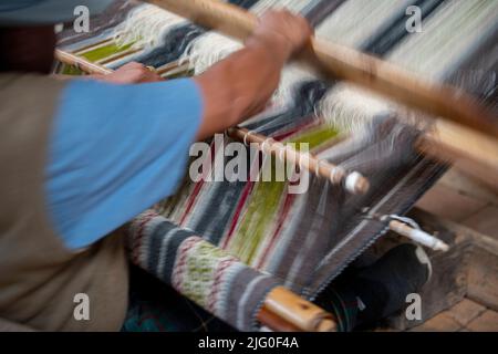Ecuador, Quito, Paguche. Tahuantinsuyo Weaving Workshop. Traditional "back strap" weaving demonstration. Action blur. Stock Photo