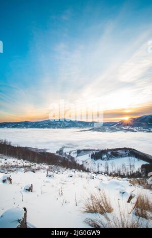Frosty morning on Skalka mountain in Beskydy mountains overlooking the valley covered with clouds and fog and a view of Lysa mountain. Snowy landscape Stock Photo