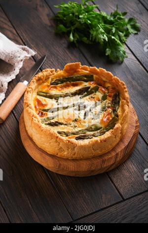 Quiche. Homemade asparagus pie or quiche with cheese and spinach on old dark wooden table background. Top view. Stock Photo