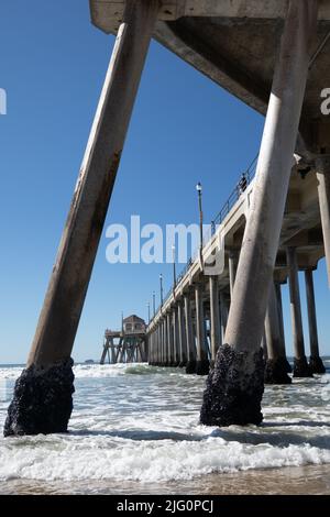 Unique view underneath Huntington Beach Pier. showing wooden structure  and sea at Huntington Beach, California USA Stock Photo