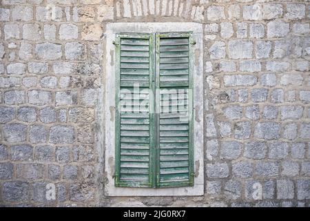 Aged wooden shutters on a window on a stone wall. Stock Photo