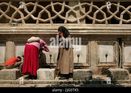 Muslim women washing their faces and hands before entering the mosque in the fountain in the courtyard of the Selimiye Mosque (Selimiye Camii) in Edirne, Turkey. The mosque designed by Ottoman imperial architect Mimar Sinan was built between 1568 and 1575. Stock Photo