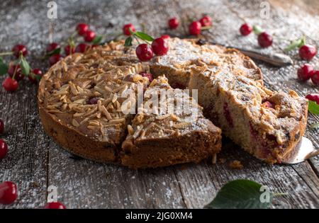 Cherry cake with almond topping on wooden table Stock Photo