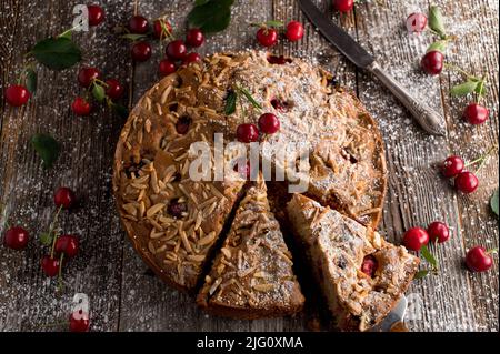 Cherry cake with almond topping on wooden table. Baked with whole wheat flour Stock Photo