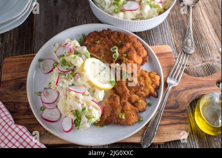 German comfort food with a fresh pan fried breaded pork "Schnitzel". Served with homemade potato salad on a plate Stock Photo