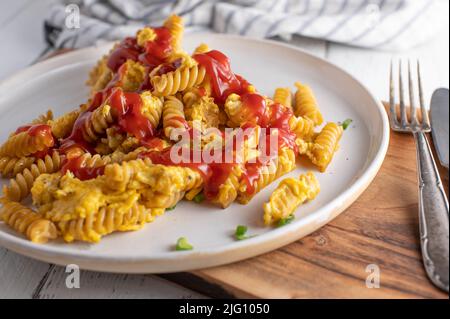 Pasta with fried eggs and ketchup. Homemade fast food. Unhealthy eating Stock Photo