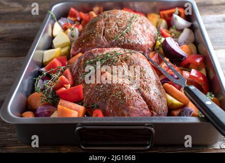 Roast pork raw and uncooked with vegetables in a roasting pan. Preparation and cooking image Stock Photo