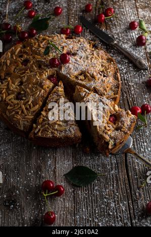 Whole wheat cake with sour cherries and almond on wooden table Stock Photo