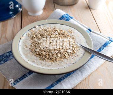 Natural and healthy breakfast with a fresh yogurt, oats and pureed apples on a plate with spoon Stock Photo