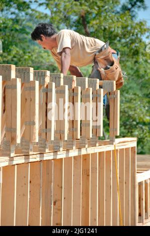 Latin work crew building wooden stick built house home cutting measure nailing on hot day Stock Photo