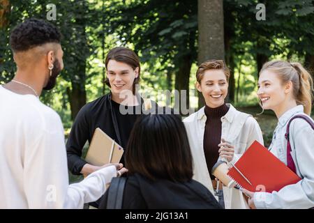Multiethnic students with notebooks talking in park Stock Photo