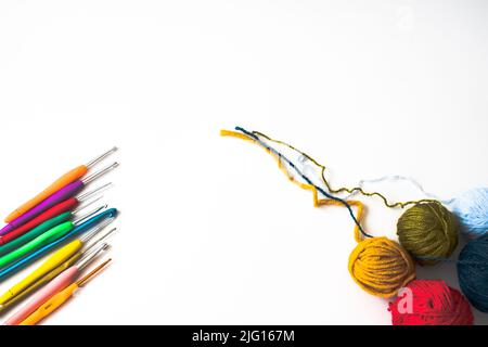 Top view of crochet hooks and balls of wool, colorful crochet hooks and balls of wool isolated on a white background. Flat lay photo. Copy space. Stock Photo