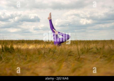 Legs in a field. woman doing a headstand in the middle of a field Stock Photo
