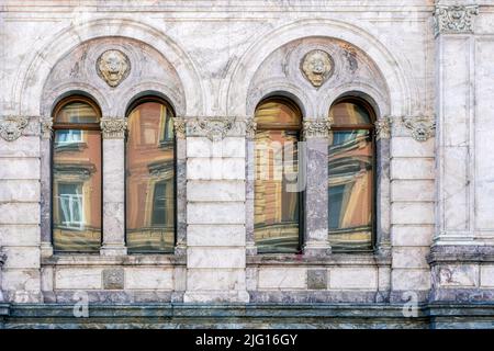 Four arched windows with a bas-relief of a lion's head against a marble stone wall. From the Windows of the world series. Stock Photo