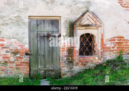 Window with bars and an old wooden door on the background of a plastered old stone wall. From the Window of the World series. Stock Photo
