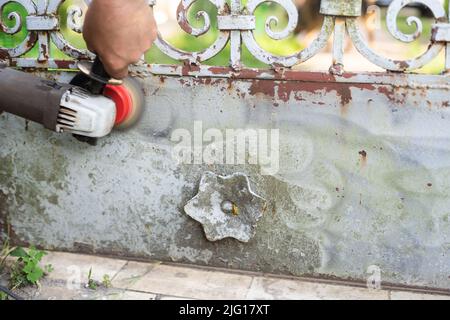 Handyman scrape the old paint from rusty fence Stock Photo