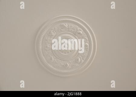 From below classic plaster floral ornament of medallion decorating ceiling above elegant chandelier at home Stock Photo