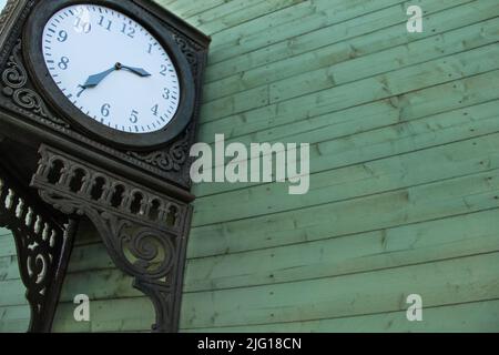 Vintage station clock with hour and minute hands. Forged stylish clock that shows time at the rail station. Stock Photo