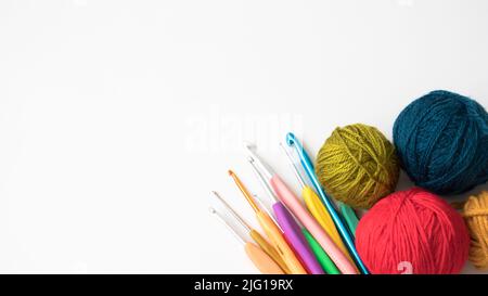 Colorful balls of wool with crochet hooks. Copy space, space for text on the left side. Top view, above, up. Flat lay photo. Stock Photo