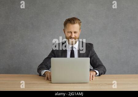 Happy smiling businessman sitting at desk using laptop studio shot portrait Stock Photo