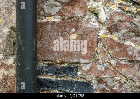Flushwork flint church wall infilled with fragments of inscribed broken foot stones in red sandstone Stock Photo