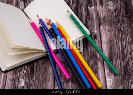 Various school supplies such as markers, colored pens and markers, notebook and eraser. On top of a wooden table. Back to school. Stock Photo