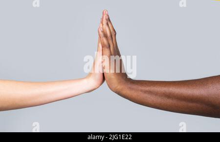 White Woman, African man giving high five, Friendship Symbol.Mixed race couple holding hands. High-five gesture and tenderness of friendship between Stock Photo