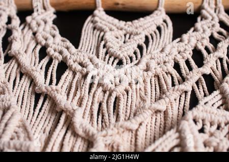 fragment of a wall decor made of woven threads in the style of macrame on a black background Stock Photo