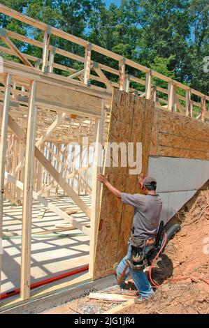 Latin work crew building wooden stick built house home cutting measure nailing on hot day Stock Photo