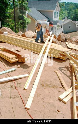 Latin work crew building wooden stick built house home cutting measure nailing on hot day Stock Photo